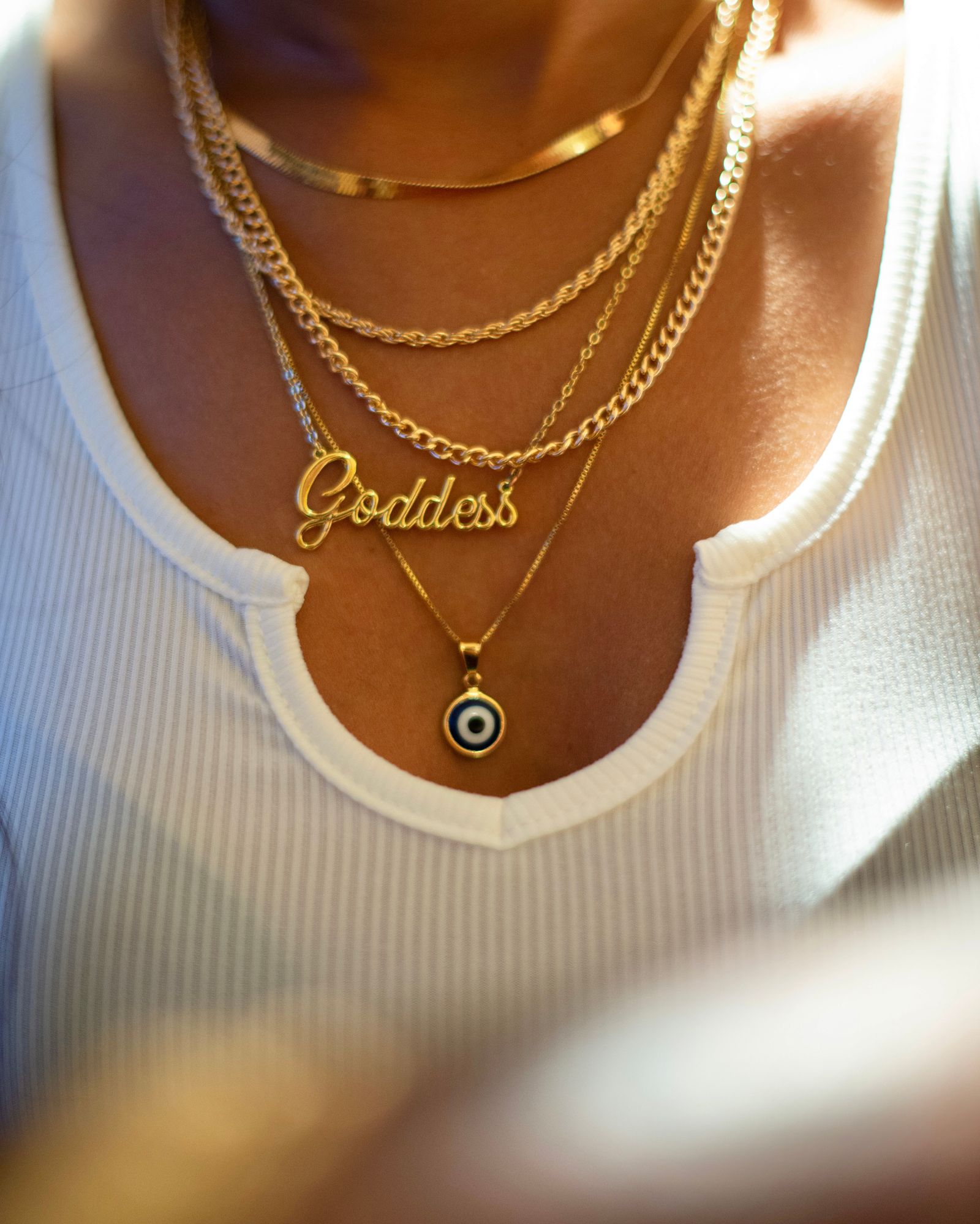 Layered gold necklaces with a pendant on a woman.