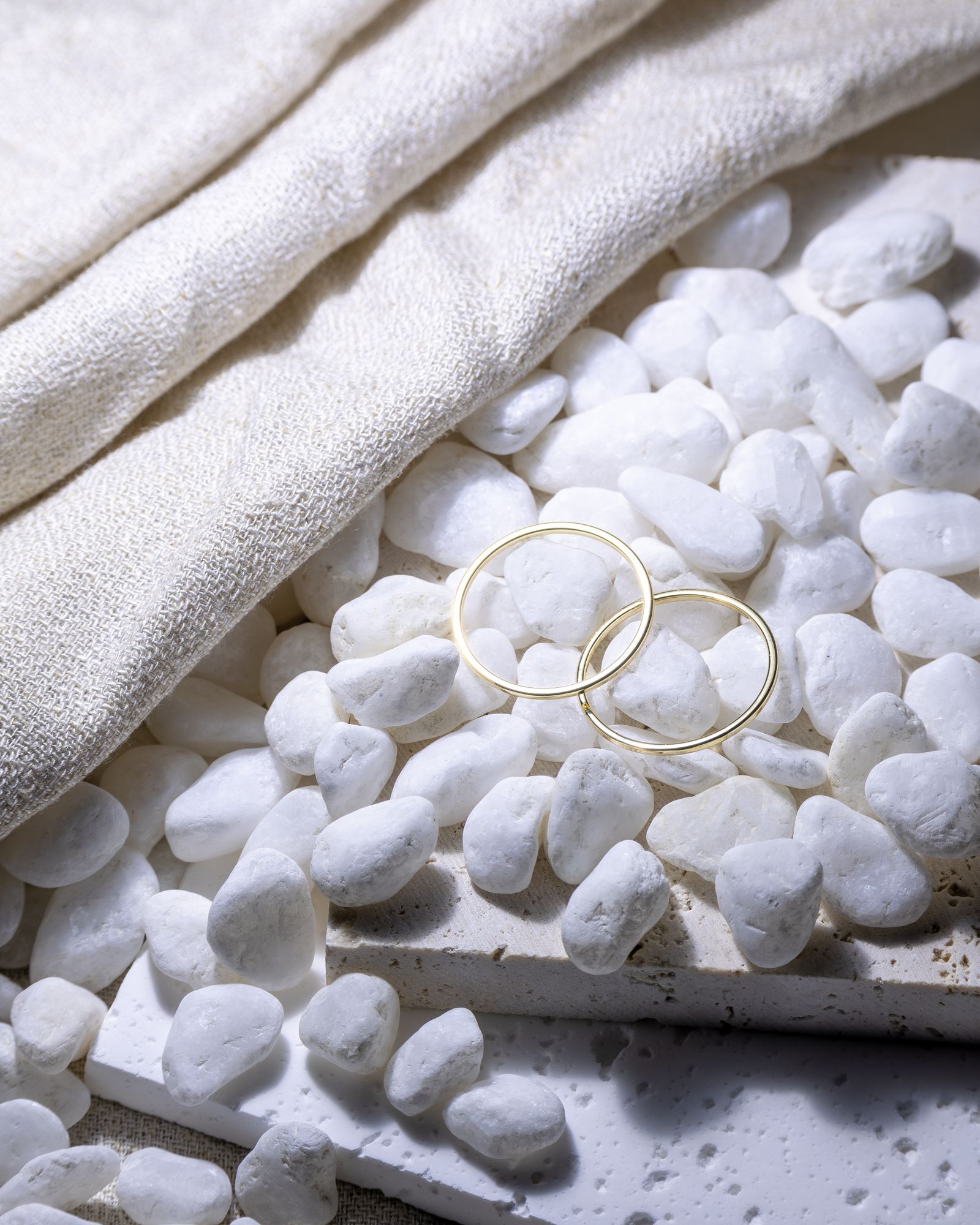 Gold rings arranged on white pebbles.