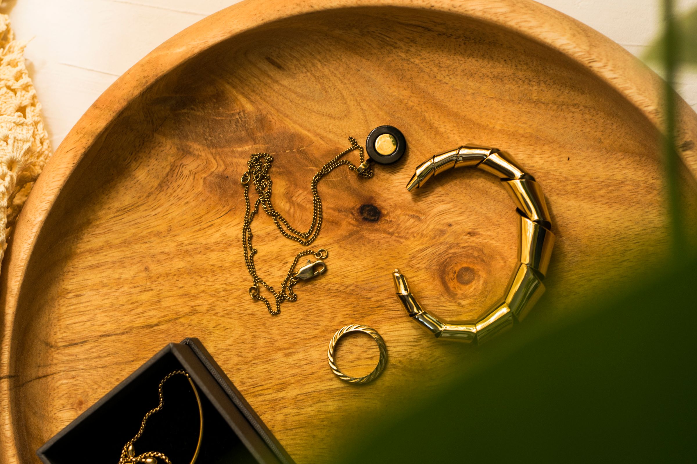 Jewellery pieces laid out on a wooden tray in natural light.