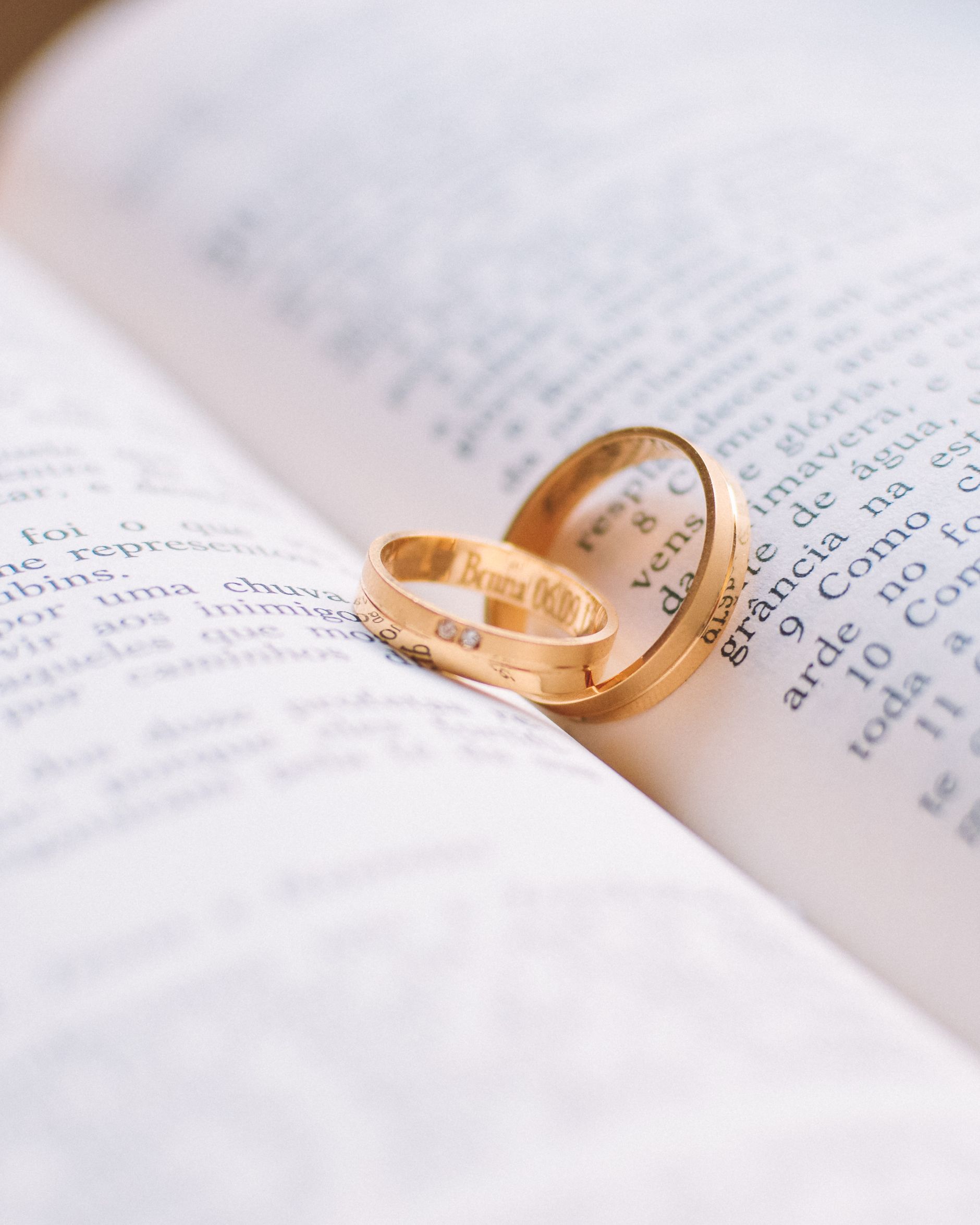 Two gold rings resting on the pages of an open book.