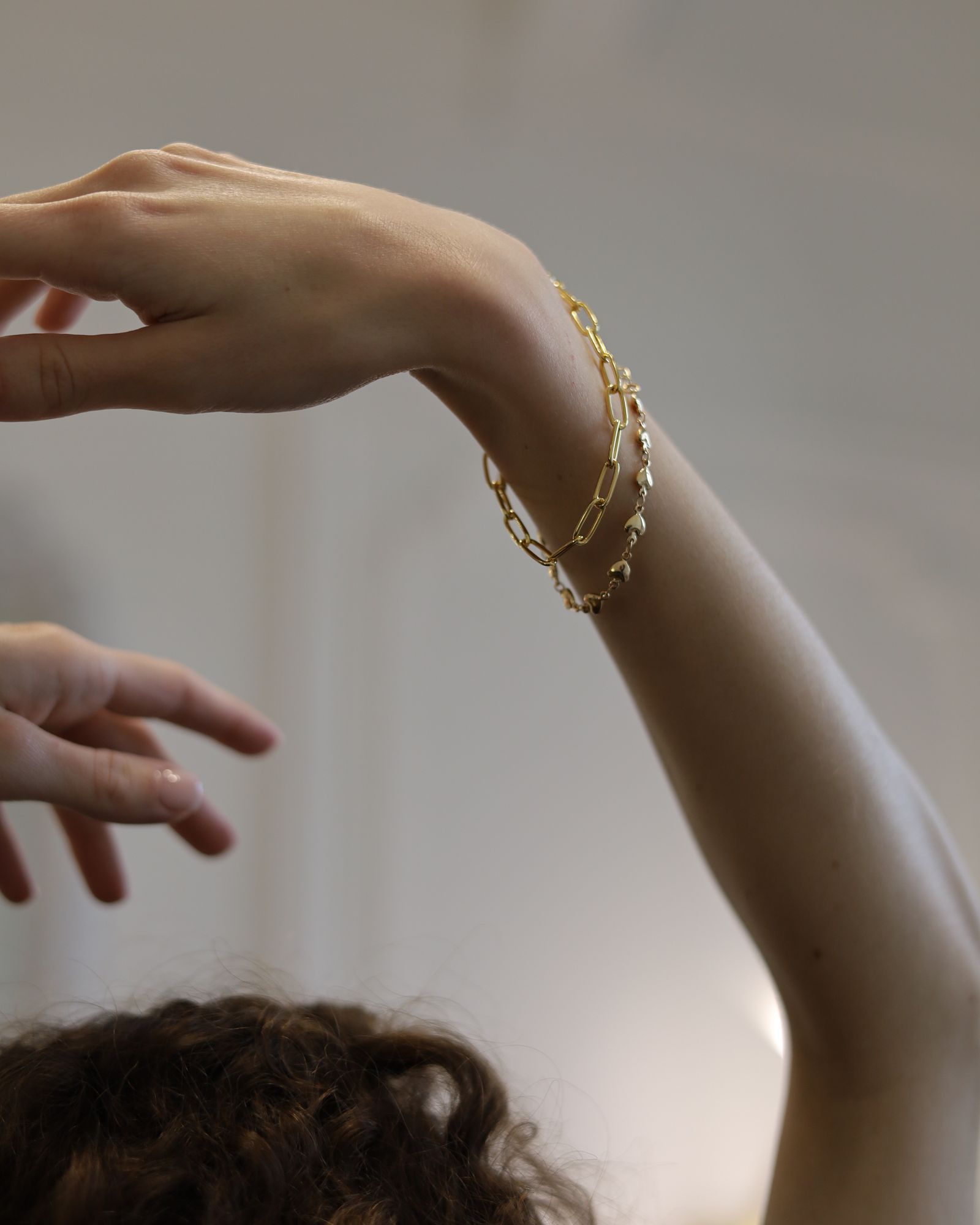 Gold bangles on an arm in an artistic pose.