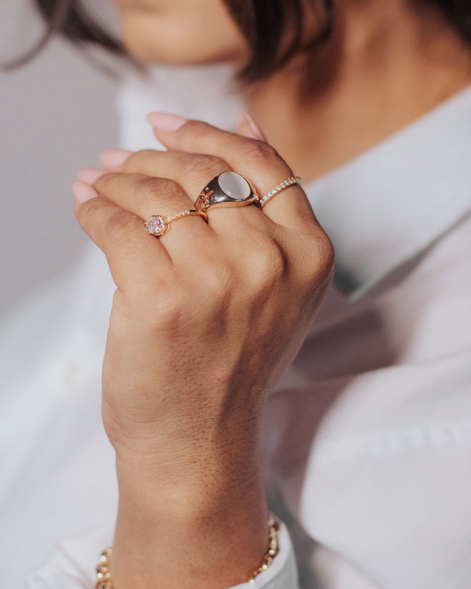 A woman's hand wearing several slim gold rings.