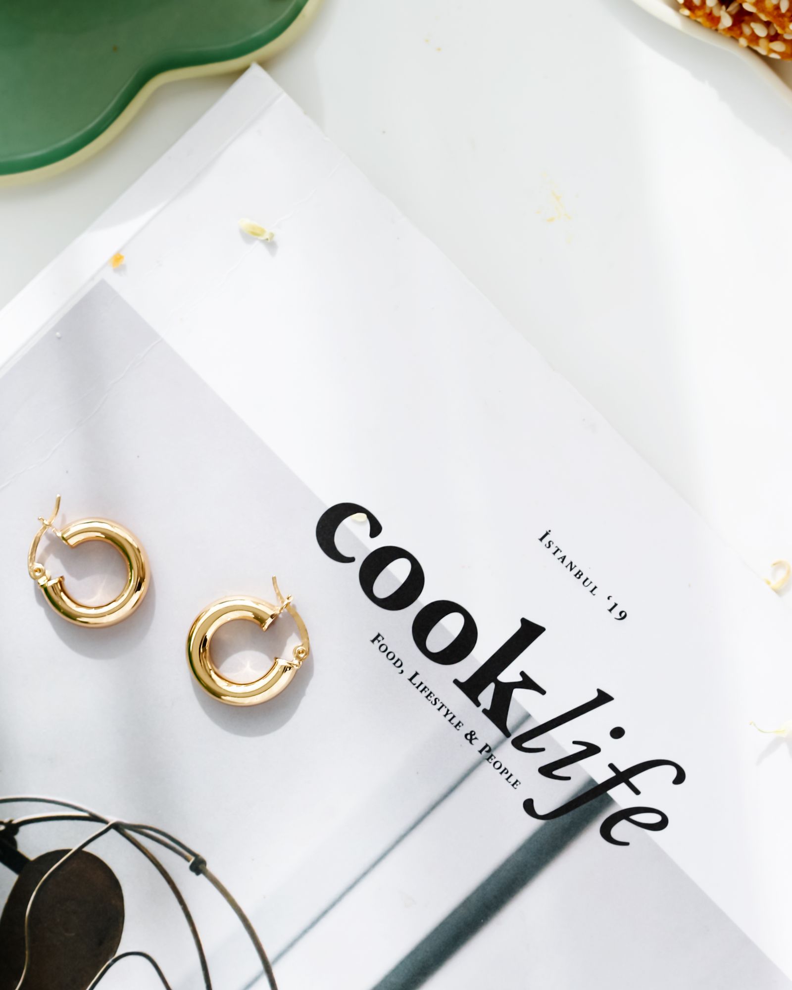 Gold hoop earrings resting on a magazine.
